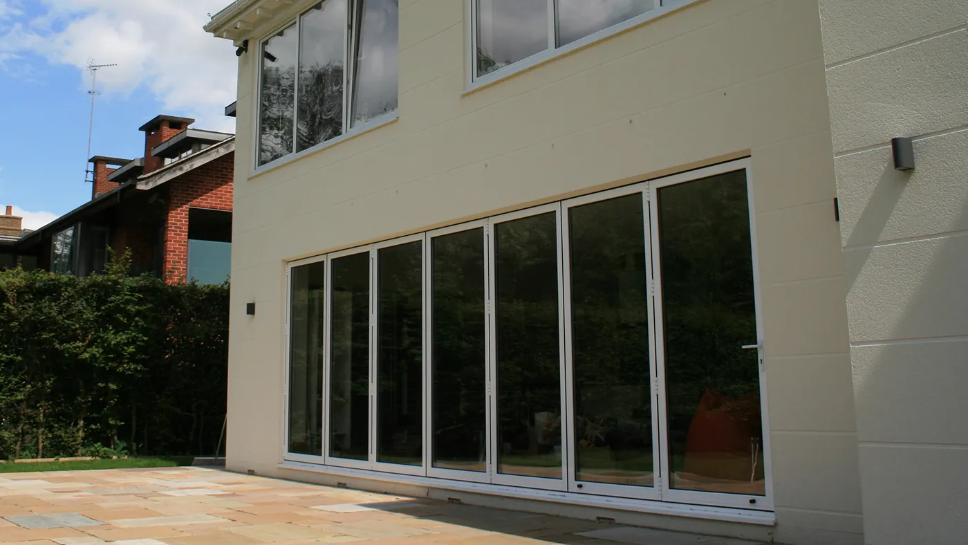 White aluminium bi-fold doors opening to patio on modern property, Ascot