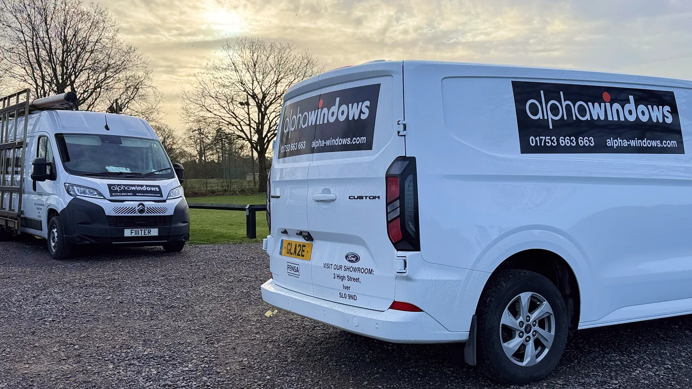 Close-up of two Alpha Windows branded vans showing company livery and contact details