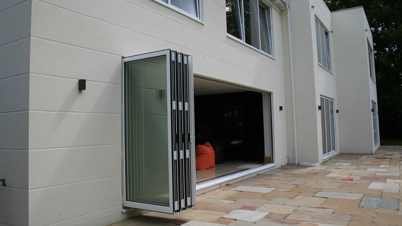 White aluminium bi-fold doors opened to patio on modern property, Ascot