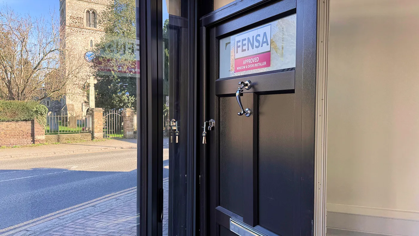 Interior of Alpha Windows showroom displaying a composite door with FENSA registered installer sticker