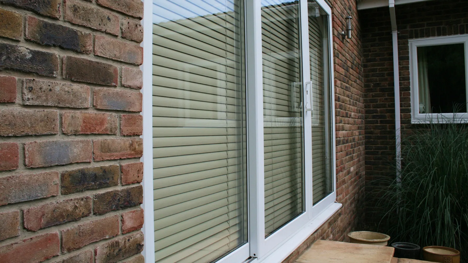 White-framed window pane with internal blinds and a handle
